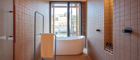 A modern bathroom with a freestanding bathtub, a glass shower enclosure, and a view of the outside.
