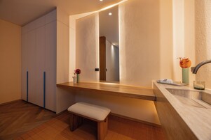 Un baño moderno con un banco de madera, un espejo grande y un lavabo.
