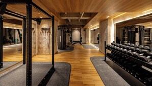 A gym with wooden floors, weight racks, and exercise equipment.