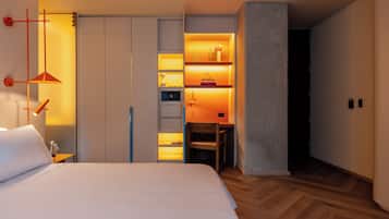 Ett modernt hotellrum med en stor säng, ett skrivbord och en inbyggd hyllsektion med böcker och dekorativa föremål.
