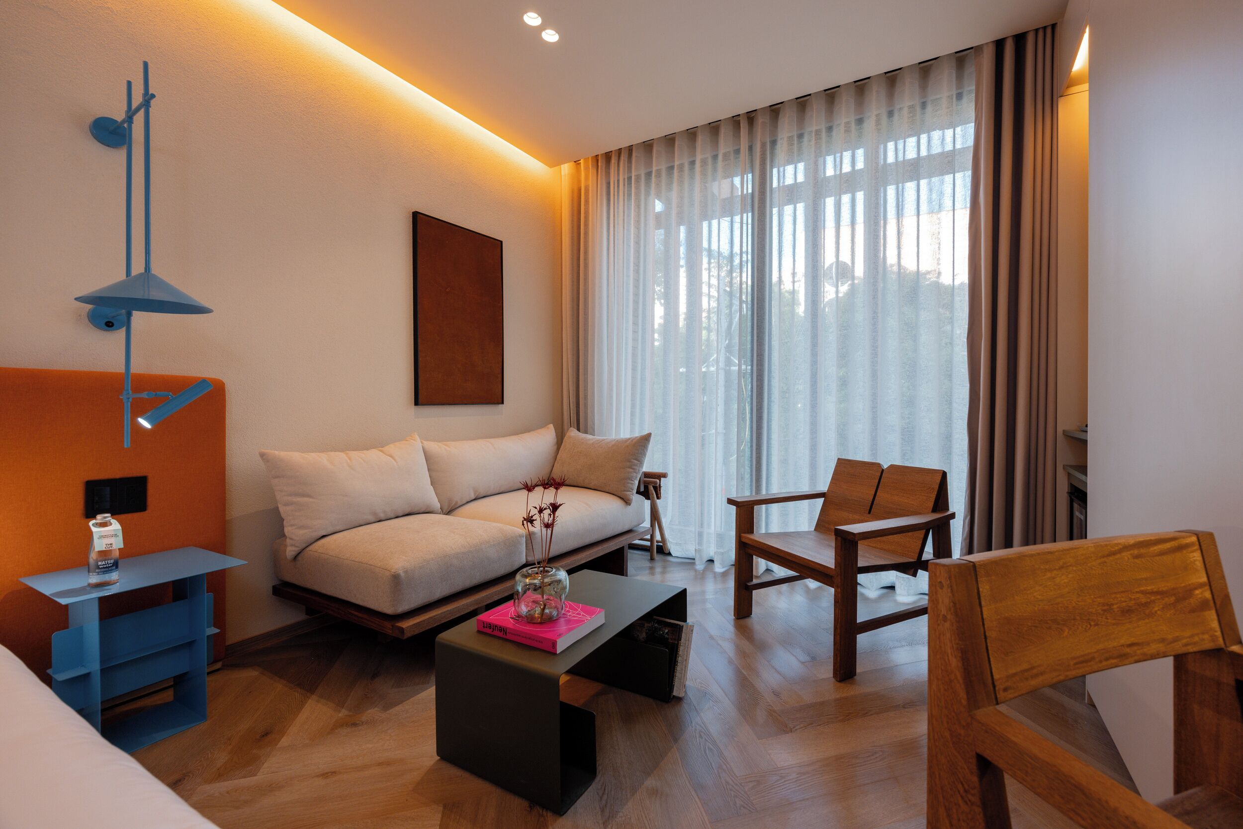 A modern living room with a sofa, a coffee table, a wooden chair, and a blue side table.