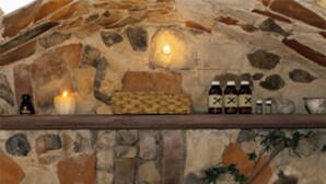 A stone-walled bedroom with a bed, a shelf with bottles, and a lit candle. - Amazing 4-Cabin "Bed & Breakfast" in Chimaltenango by Johnson (Chimaltenango)