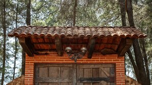 A rustic wooden door with a metal gate, set in a stone wall with a tiled roof. - Amazing 4-Cabin "Bed & Breakfast" in Chimaltenango by Johnson (Chimaltenango)