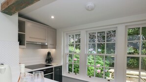 Une cuisine dotée d’un plan de travail blanc, d’une cuisinière et d’une fenêtre donnant sur un paysage verdoyant.