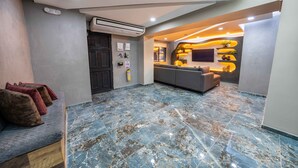 Een modern interieur met een marmeren vloer, een bank met kussens, een donkere deur en een wandairconditioner.