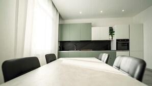 A modern kitchen with a dining table and chairs, a coffee machine, and a built-in oven. - HouSmart Fiesso 9 (Castenaso)