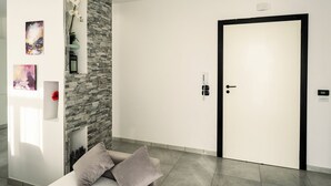 A modern hotel room with a stone accent wall, a bed with pillows, a door with a keycard lock, and artwork on the walls. - HouSmart Fiesso 9 (Castenaso)