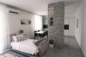 A modern bedroom with a bed, a dining table, and a kitchen area. - HouSmart Fiesso 9 (Castenaso)