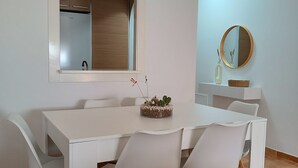 A dining area with a white table and chairs, a window with a view of a kitchen, and a round mirror on the wall. - Apartment in Vera playa. Between Sol and Salinas (AN)