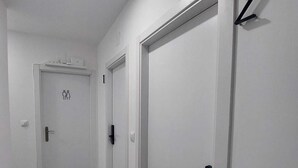 Un couloir avec deux portes, dont une porte portant le numéro 2 et une autre porte ornée du symbole indiquant les toilettes pour hommes et pour femmes.