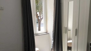 Une chambre à coucher avec un lit, une armoire et une fenêtre avec des rideaux.
