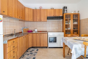 Eine Küche mit Holzausstattung, einem Herd, einer Spüle und einem Esstisch mit Tischdecke.