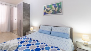 Un dormitorio con cama, mesita de noche, lámpara, un cuadro y zona de ducha.