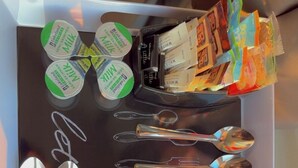 Una bandeja con varios objetos, incluyendo envases de leche, un bate de béisbol, cucharas y vasos.