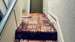 Una escalera estrecha con una alfombra estampada que conduce a una puerta con el número "024".