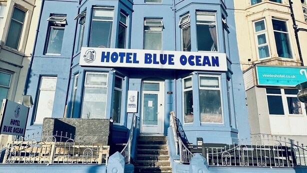 Un edificio con un cartel que dice 'HOTEL BLUE OCEAN' y una escalera que conduce a la entrada.