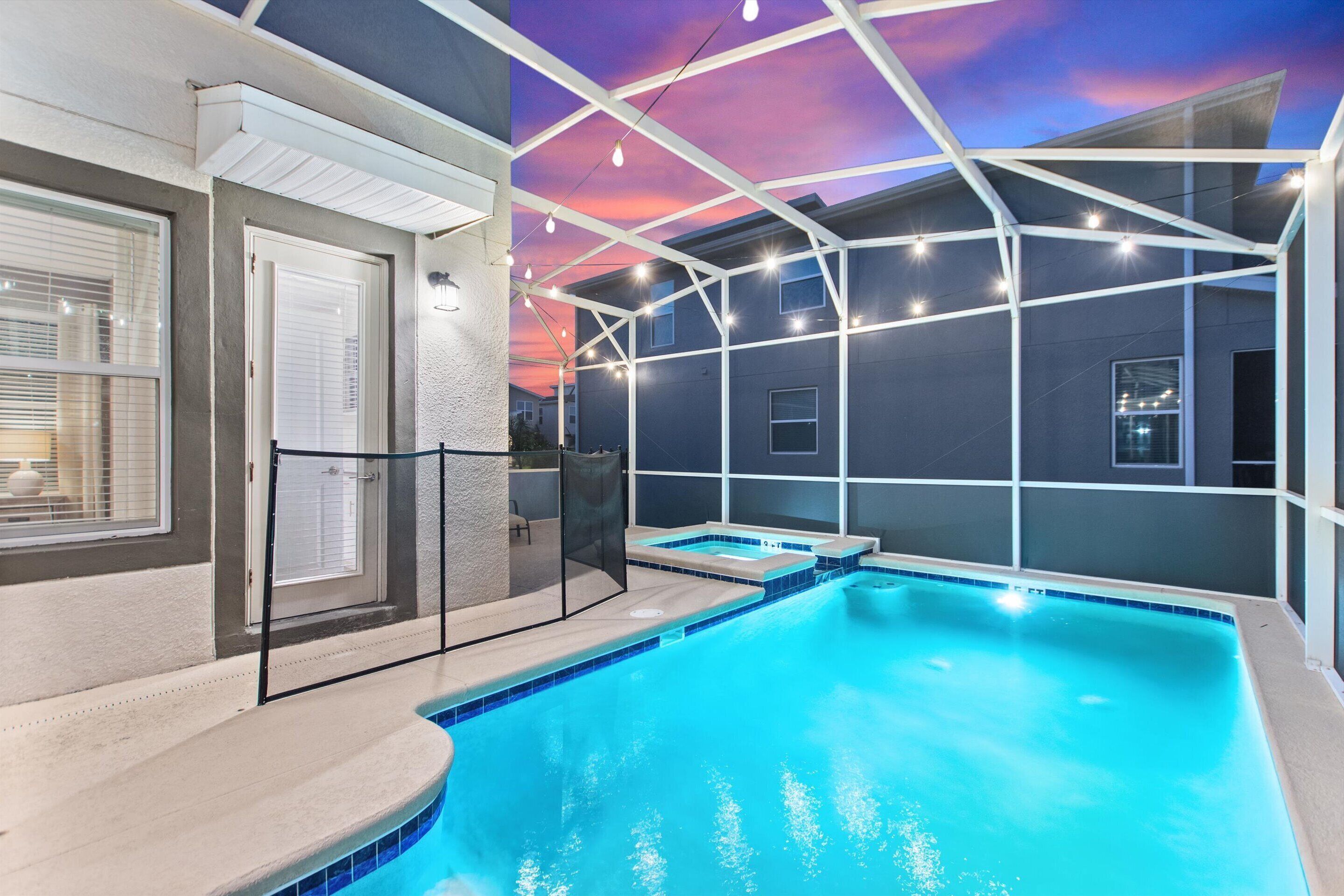 A swimming pool with a modern architectural design, including a covered area with string lights and a clear view of the sky.