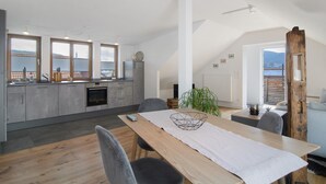 Cocina moderna con zona de comedor, ventanas amplias y vistas a las montañas.