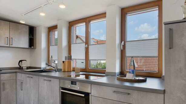 Una cocina moderna con horno empotrado, electrodomésticos de acero inoxidable y ventanas amplias.