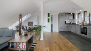 Un loft moderno con comedor, cocina y dormitorio en entrepiso con tragaluz.
