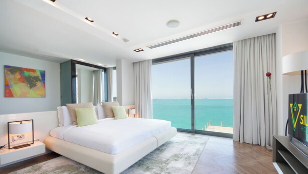 Un dormitorio moderno con una cama grande, televisión y vistas al mar.
