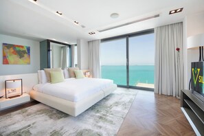 Un dormitorio moderno con una cama grande, televisión y vistas al mar.