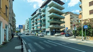 A multi-story residential building with balconies, a pedestrian crossing, and parked cars on a city street. - Casa Vacanza Appartamento Irnerio (Rome)