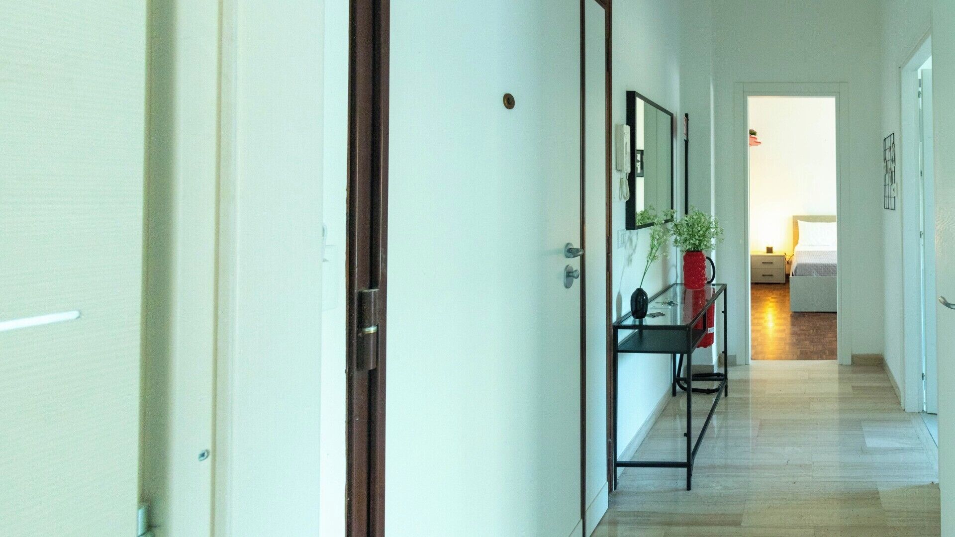 Un couloir comprenant un lit, une table de chevet et un miroir.