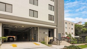 Un bâtiment moderne avec une entrée de garage, un escalier menant à l’entrée et un ciel dégagé.