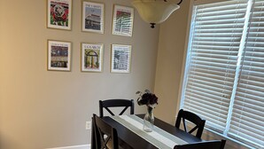 A dining room with a dark wooden table and chairs, a vase with flowers, and framed pictures on the wall. - Charming 3BR 2BA 20 min drive to the Masters (Grovetown)