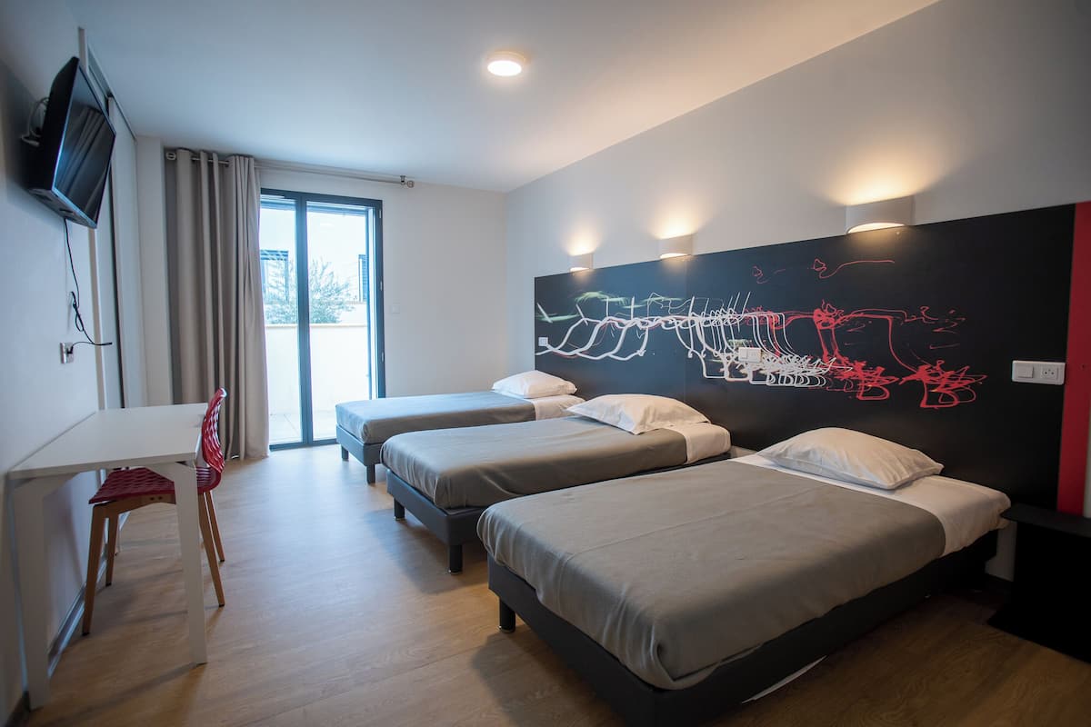 A hotel room with two beds, a desk, and a chair.
