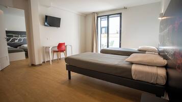 Una habitación de hotel moderna con una cama grande, un escritorio, una silla y un televisor en la pared.