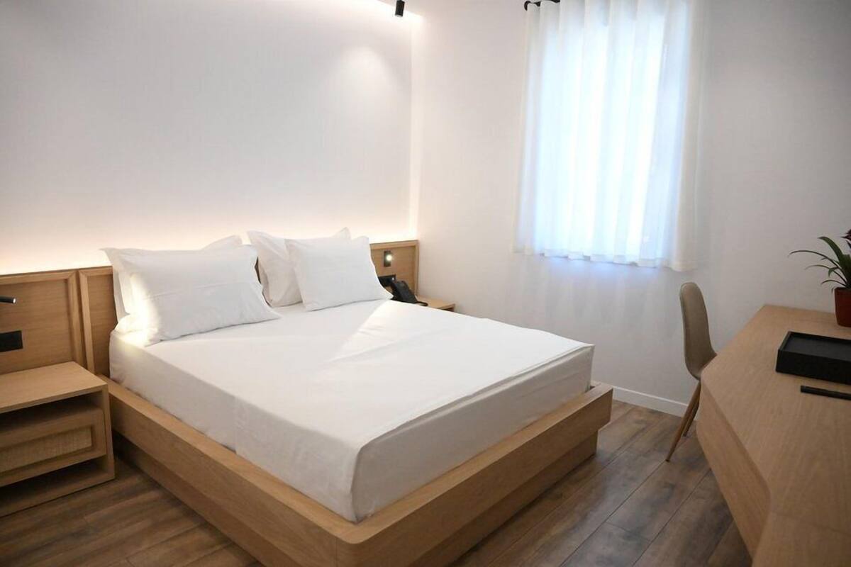 Une chambre d’hôtel moderne avec un lit en bois, un bureau et une chaise.