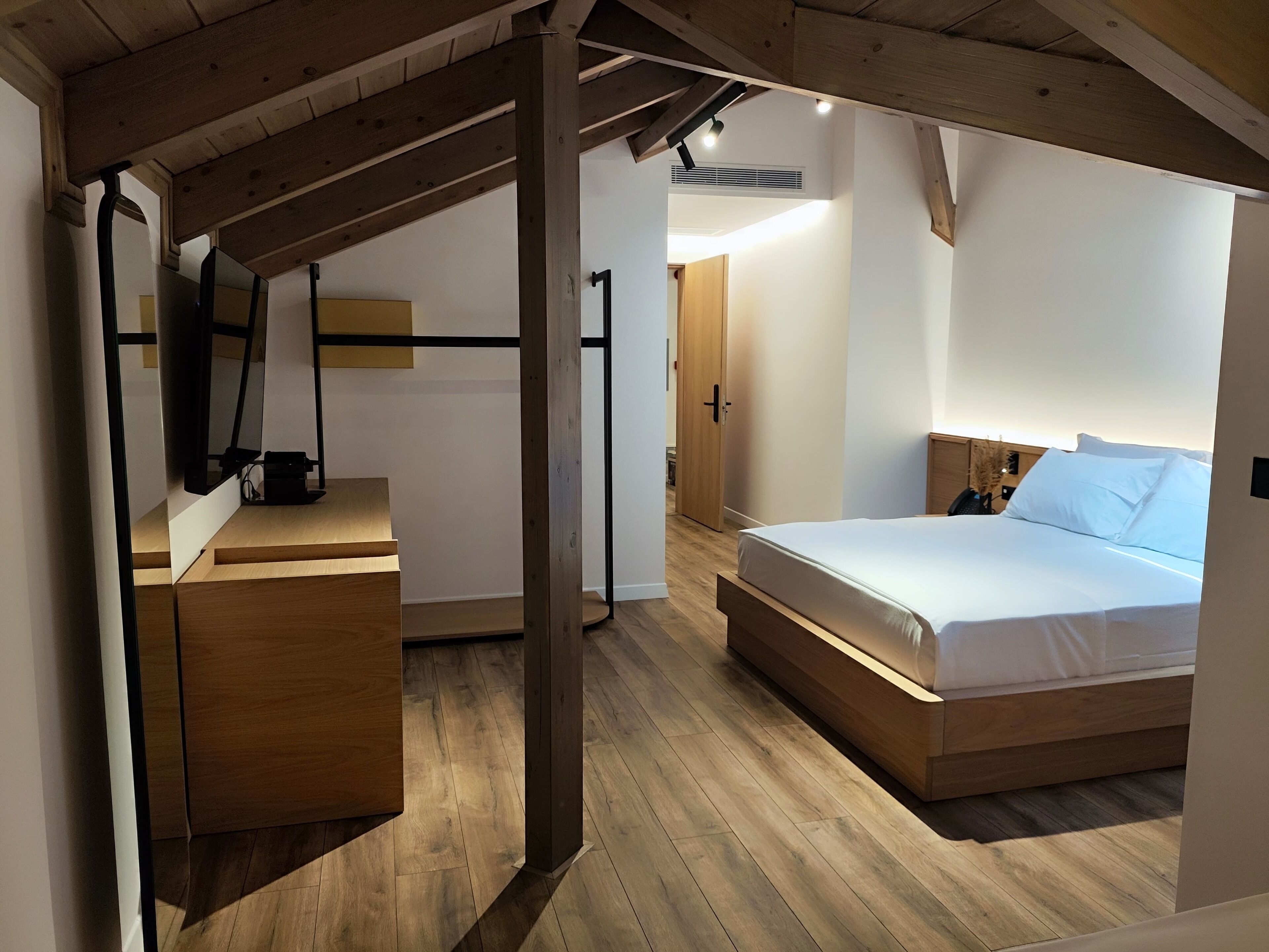 Un dormitorio moderno con cama de madera, un escritorio y un armario.