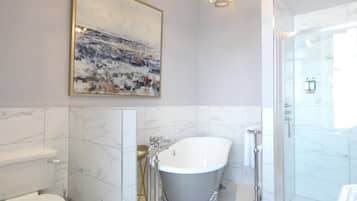 Un baño moderno con una bañera independiente, un box de ducha de vidrio y piso de baldosas de mármol.