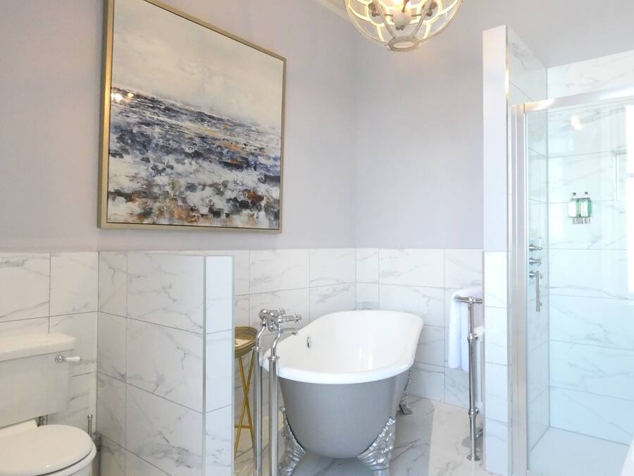 Un baño moderno con una bañera independiente, un box de ducha de vidrio y piso de baldosas de mármol.