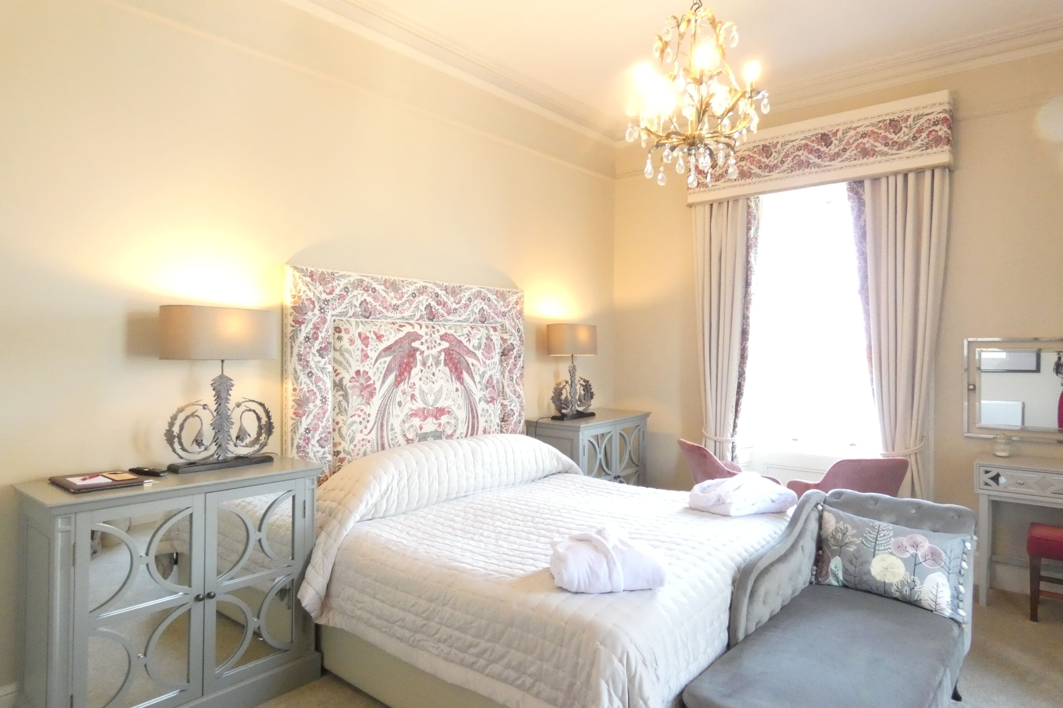 A hotel room with a large bed, two bedside tables, a desk, and a chair.
