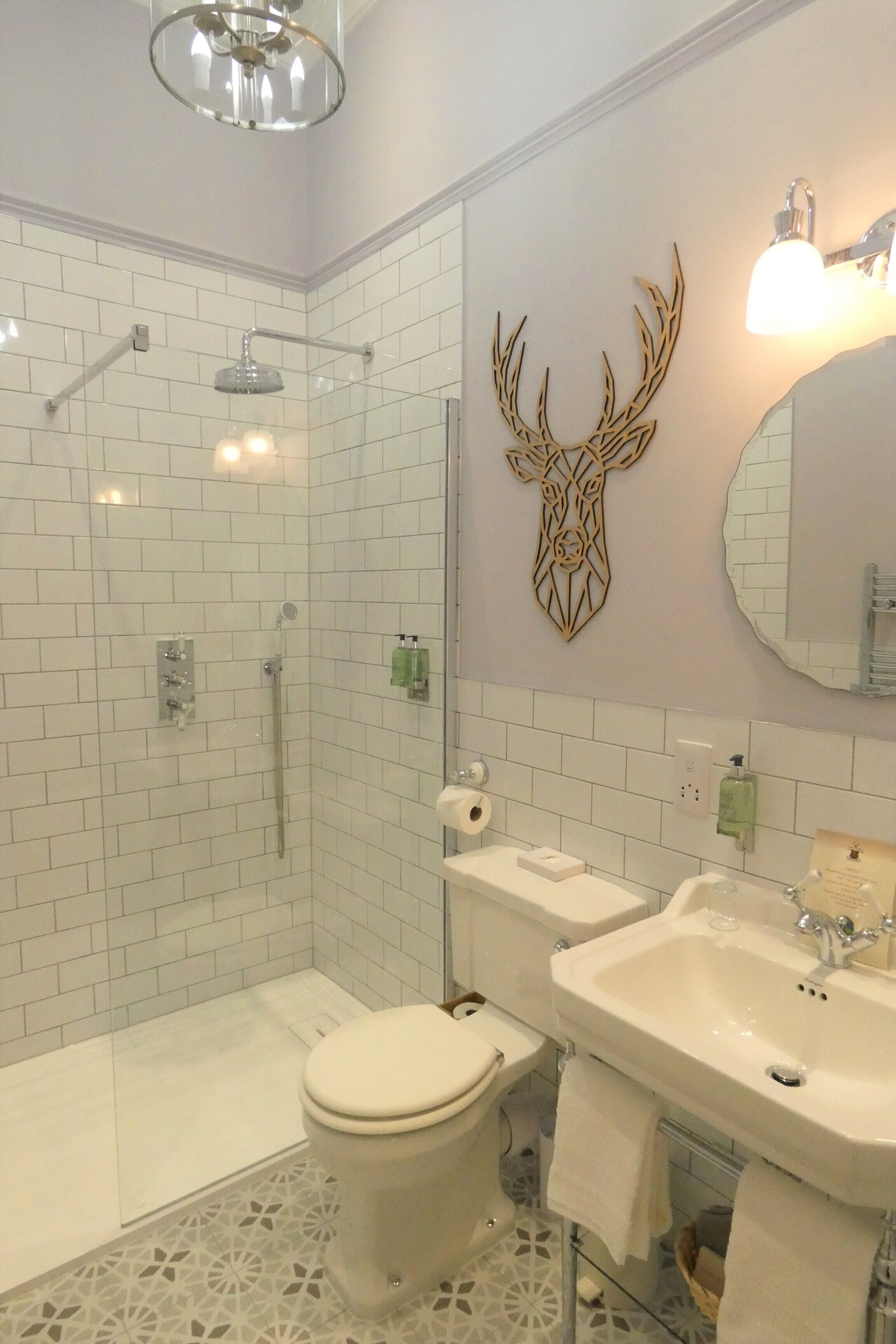 A bathroom with a shower, toilet, sink, and decorative wall art.