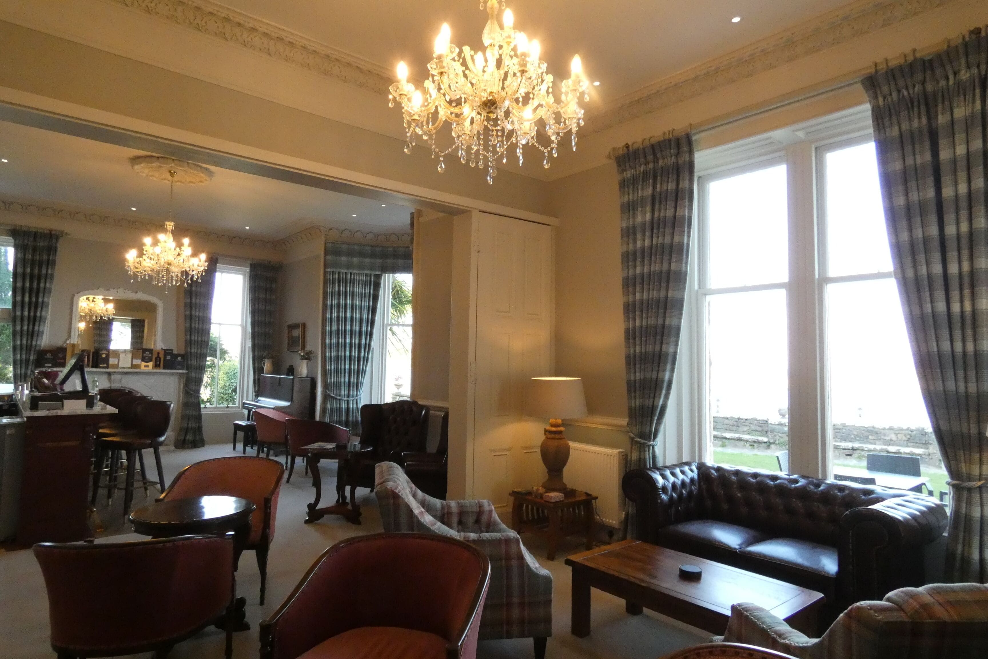 A spacious living room with a chandelier, a sofa, and a coffee table. There is a dining area with chairs and a table.
