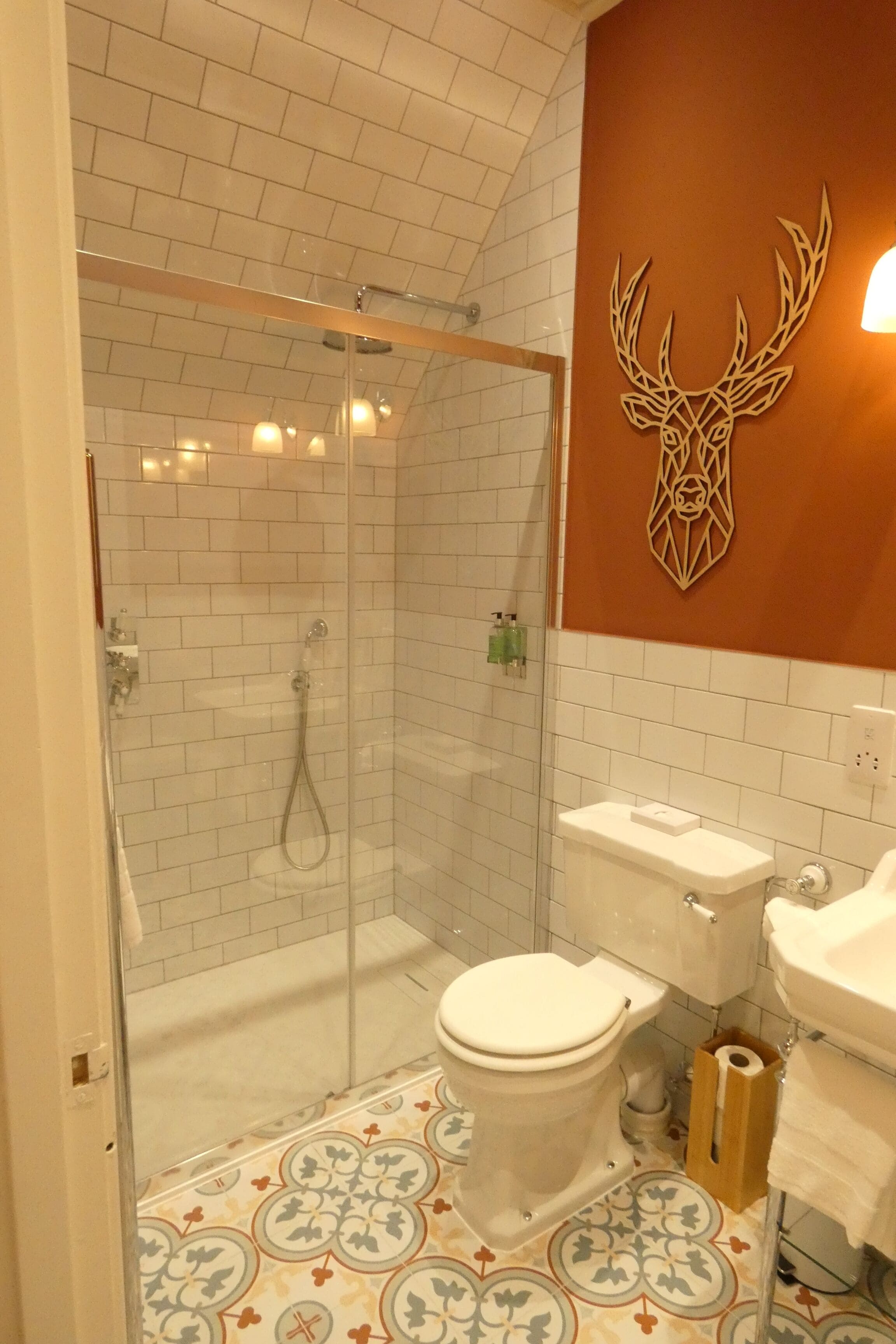 Ein Badezimmer mit Duschkabine, Toilette, Waschbecken und einem dekorativen Hirschkopf an der Wand.