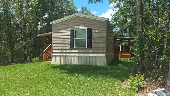 A small, single-story cabin with a front porch and a covered deck area.