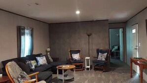 Un salon moderne comprenant un canapé, deux fauteuils, une table basse et un lampadaire.