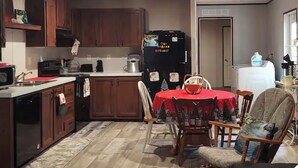 Une cuisine avec des meubles de rangement en bois, un réfrigérateur, un four à micro-ondes et une table à manger avec des chaises.