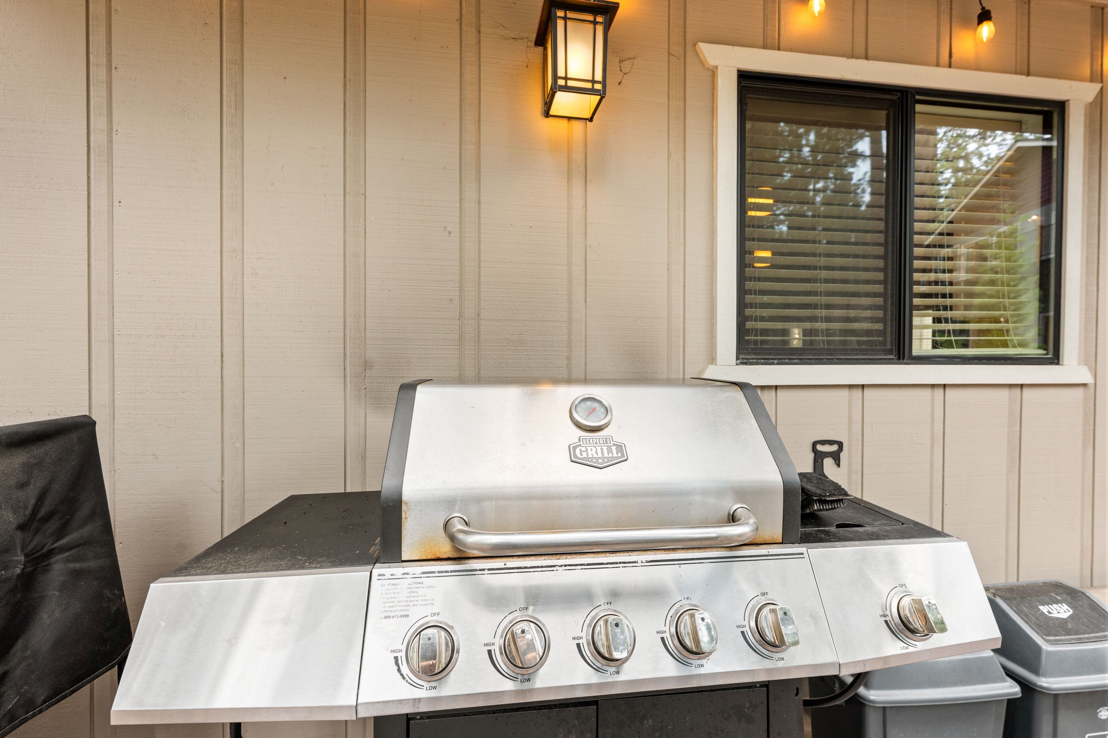 An outdoor grill with four burners, a thermometer, and a push button.