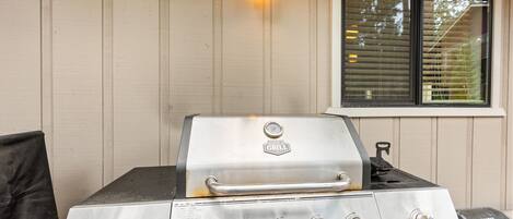 An outdoor grill with four burners, a thermometer, and a push button.