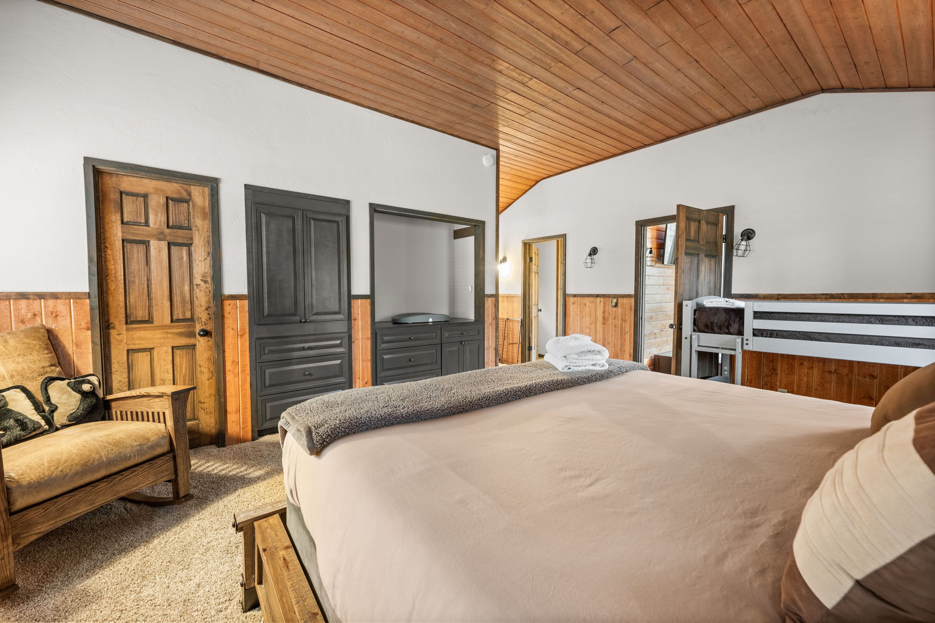 A bedroom with a bed, a wooden bench, a dresser, and a mirror.