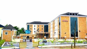 A multi-story hotel with a stone facade, large windows, and a prominent sign. - IMMACULATE ROYAL INTERNATIONAL HOTEL (Owerri)
