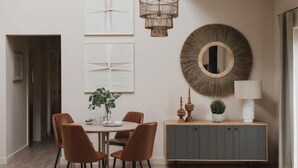 A dining area with a round table, four chairs, a cabinet, and wall decorations.