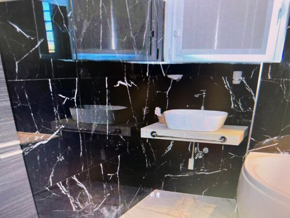 A bathroom with black marble walls, a white sink, and a white shelf. - B&B Garden Grazia (Noto)