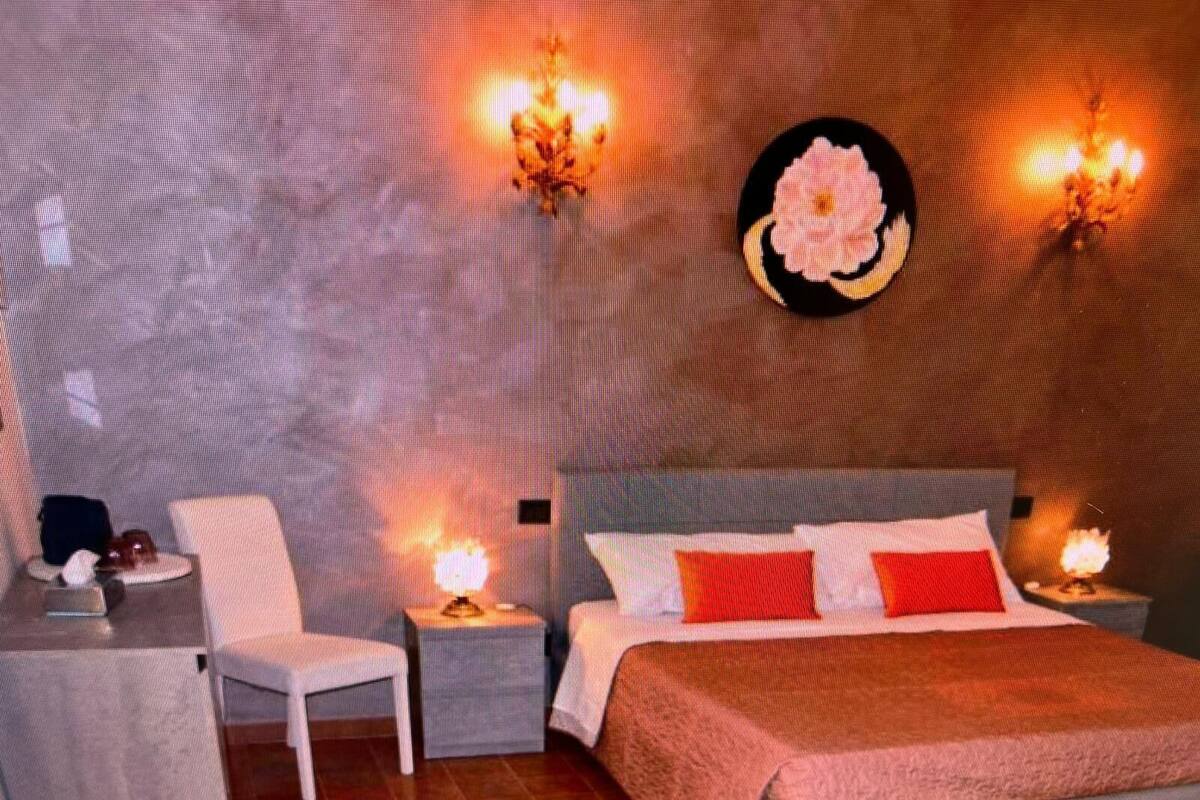 Een moderne slaapkamer met een groot bed, twee nachtkastjes, een stoel en decoratieve wandlampen.